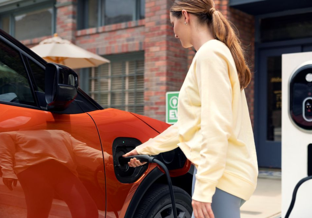 Woman in a yellow shirt charging 2026 Subaru Uncharted EV SUV